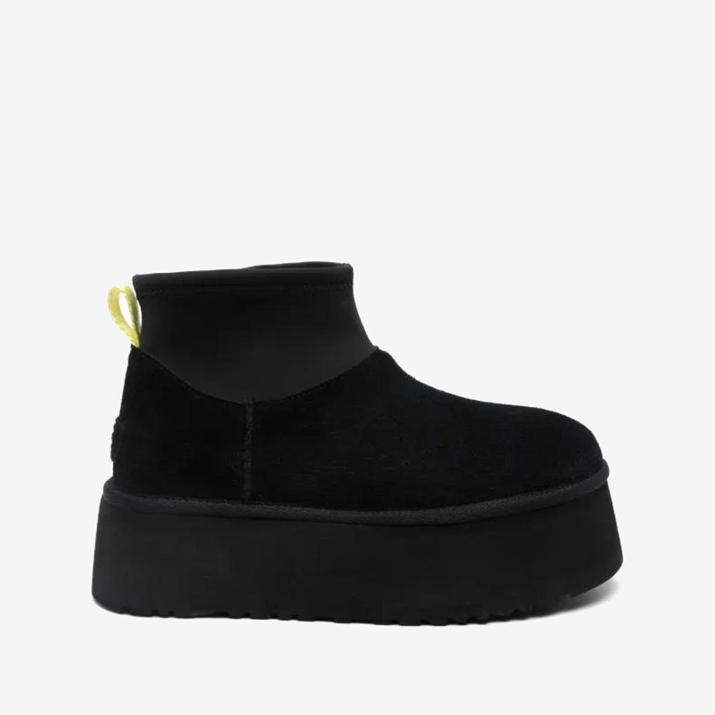 UGG Mini Dipper noire à tige courte et semelle épaisse noire, boucle arrière jaune clair, vue de profil