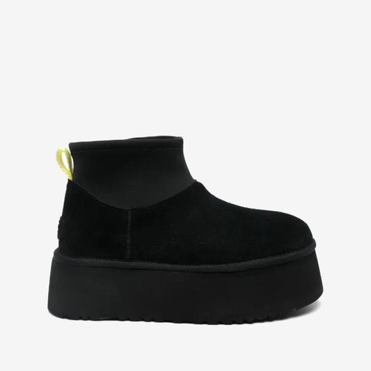UGG Mini Dipper noire à tige courte et semelle épaisse noire, boucle arrière jaune clair, vue de profil